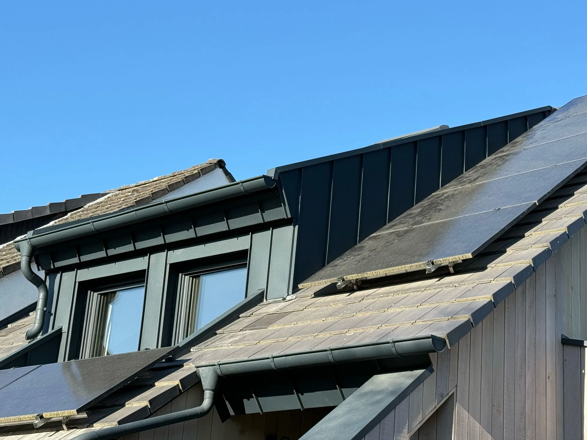 Zwei Gauben mit Stehfalz-Bekleidung, Dachrinne und Photovoltaik-Modulen auf dem Dach