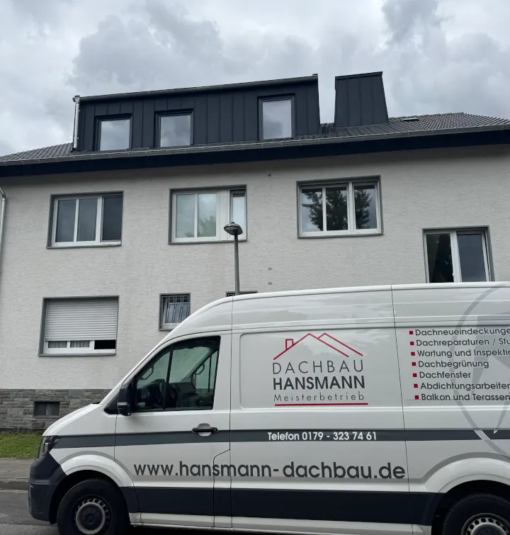 Mehrfamilienhaus mit neuen Gauben in Stehfalz-Bekleidung, davor der Firmenwagen von Dachbau Hansmann